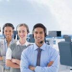 Call center executive wearing headphones and standing with arms crossed in office